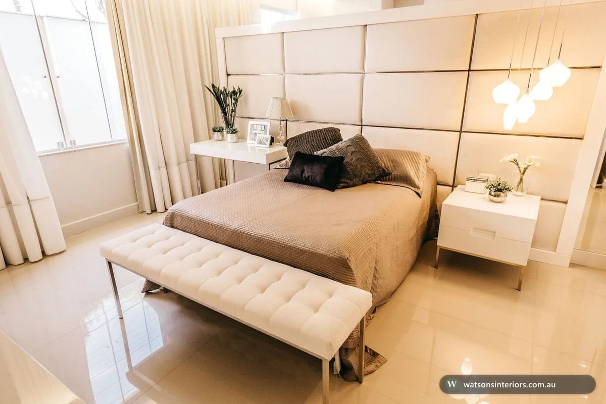 A modern Australian bedroom with a low timber bed, neutral linen bedding and warm layered lighting